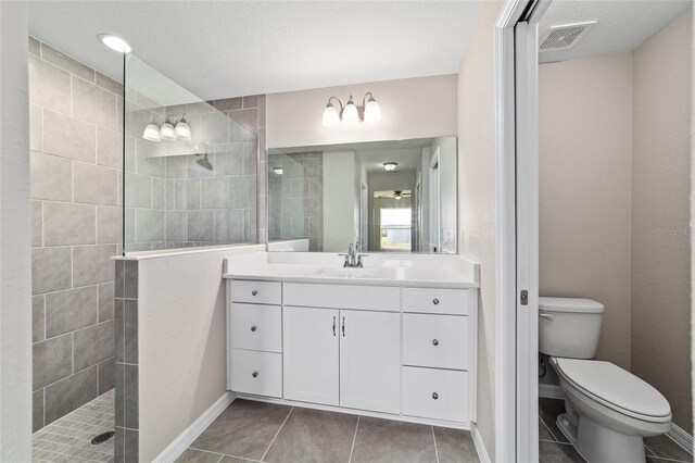 bathroom featuring a walk in shower, toilet, vanity, and tile patterned floors