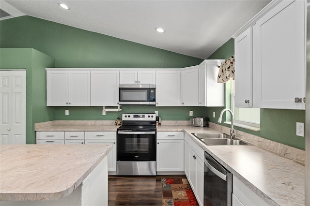 kitchen with dark wood-style flooring, lofted ceiling, light countertops, a sink, and appliances with stainless steel finishes