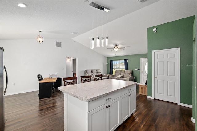 kitchen with a kitchen island, dark wood-style flooring, visible vents, light countertops, and lofted ceiling