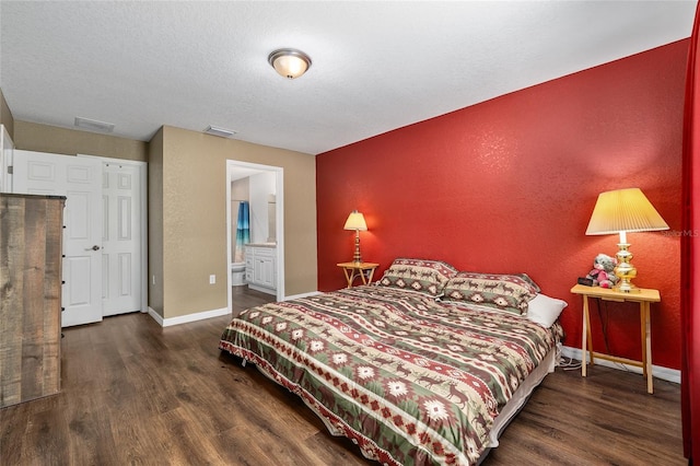 bedroom featuring baseboards, visible vents, wood finished floors, and ensuite bath