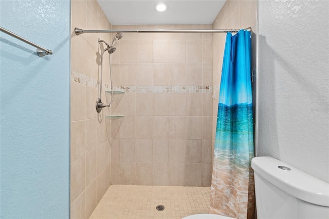 bathroom featuring a textured wall, a shower stall, and toilet
