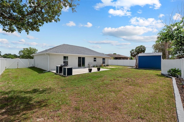view of yard featuring a storage unit, a fenced backyard, a gate, an outbuilding, and a patio