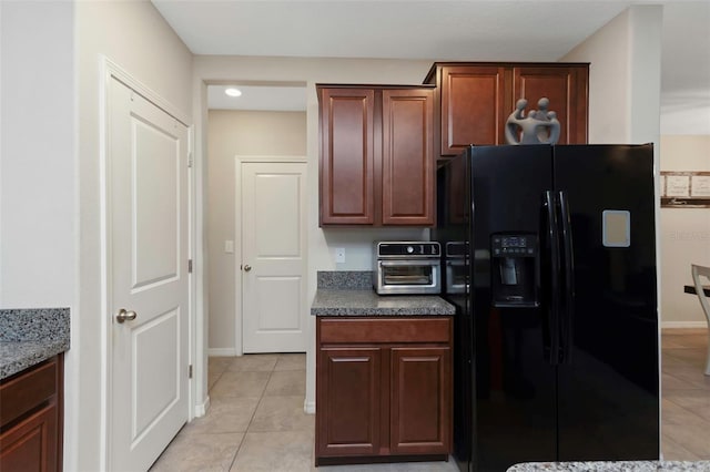 kitchen featuring baseboards, a toaster, light tile patterned floors, and black fridge with ice dispenser