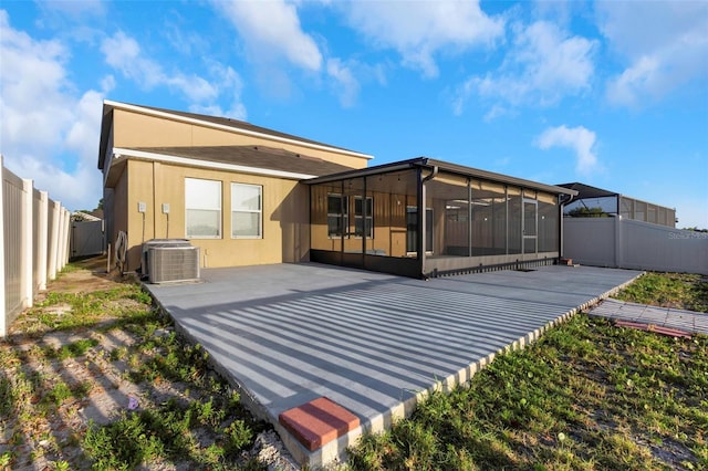rear view of property featuring a sunroom, central AC unit, a fenced backyard, and a patio