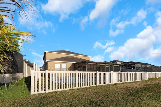 rear view of property featuring a lawn, fence, and a sunroom