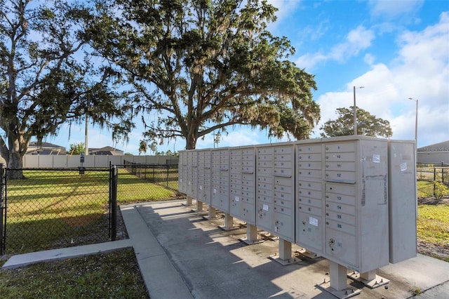 surrounding community with a lawn, fence, and mail area