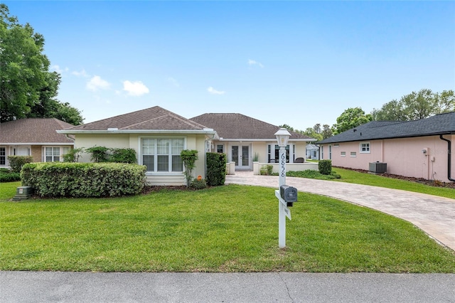 6858 SW 111th Loop, Ocala, FL 34476 - ranch-style house featuring stucco siding, driveway, central AC unit, and a front lawn