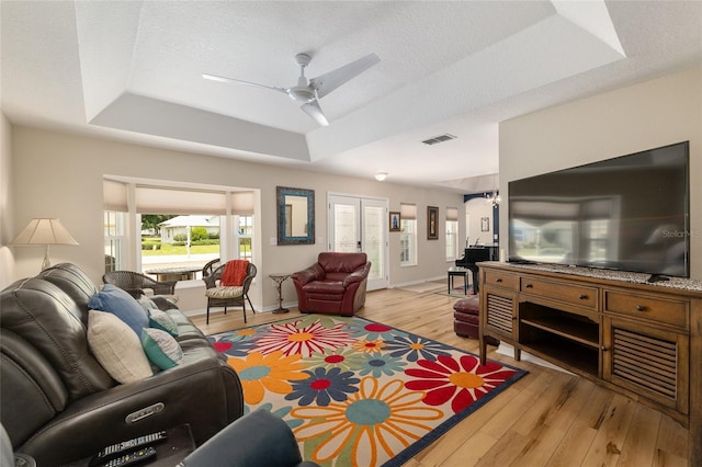 6858 SW 111th Loop, Ocala, FL 34476 - living room with a ceiling fan, visible vents, baseboards, light wood-style floors, and a tray ceiling