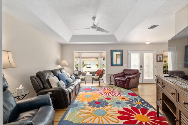 6858 SW 111th Loop, Ocala, FL 34476 - living room with a ceiling fan, a textured ceiling, visible vents, a raised ceiling, and light wood-style flooring