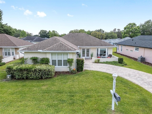 6858 SW 111th Loop, Ocala, FL 34476 - single story home with a front lawn, cooling unit, curved driveway, stucco siding, and french doors
