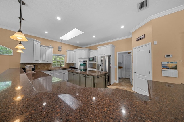 kitchen with appliances with stainless steel finishes, a sink, backsplash, a skylight, and visible vents