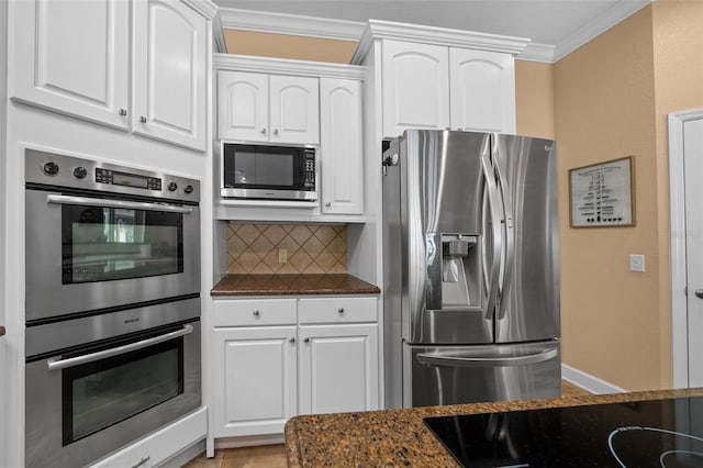 kitchen featuring ornamental molding, white cabinetry, tasteful backsplash, dark stone countertops, and stainless steel appliances
