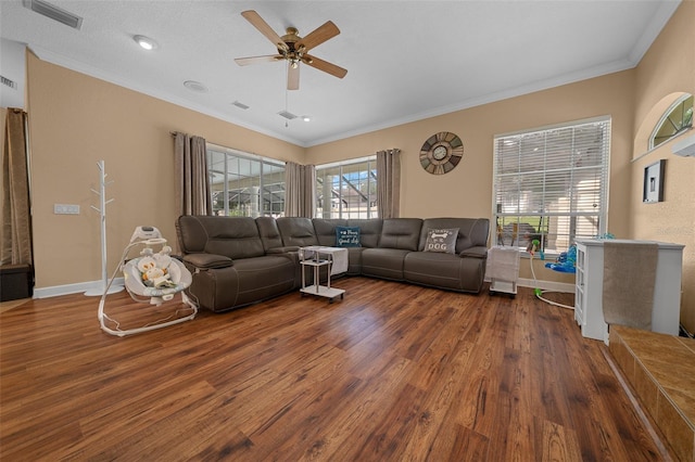 living area featuring ceiling fan, visible vents, wood finished floors, baseboards, and ornamental molding