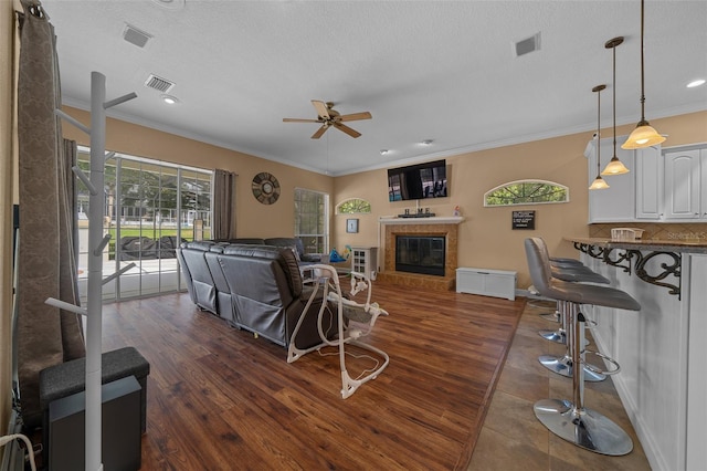 living area featuring crown molding, a ceiling fan, and visible vents