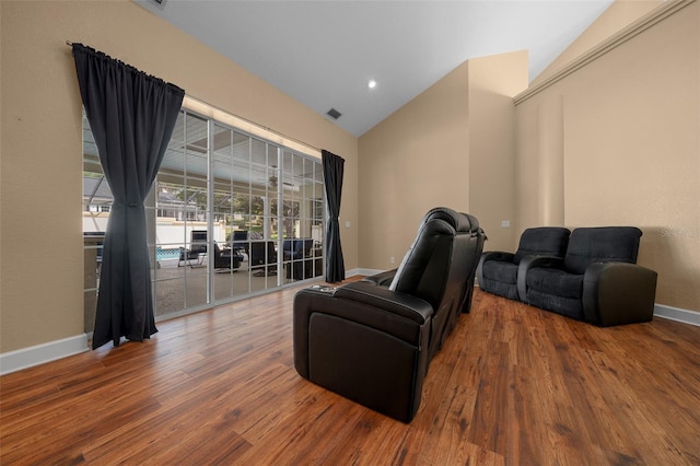 interior space with baseboards, vaulted ceiling, wood finished floors, and visible vents
