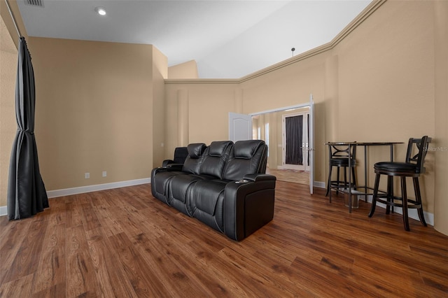 cinema room with baseboards, high vaulted ceiling, and wood finished floors
