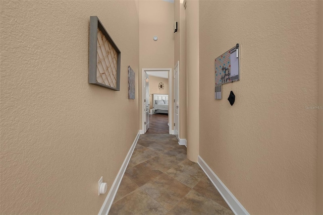 corridor featuring baseboards and a textured wall