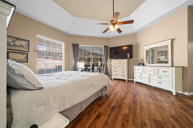 bedroom featuring baseboards, ceiling fan, wood finished floors, and a raised ceiling