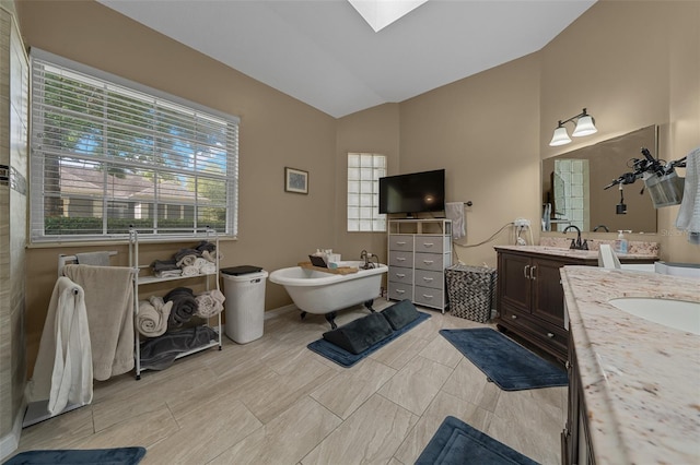 bathroom featuring a freestanding tub, two vanities, a sink, and high vaulted ceiling