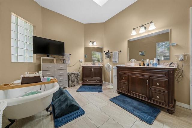 full bath featuring a sink, a high ceiling, two vanities, and a soaking tub