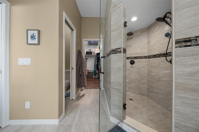 full bathroom with baseboards, toilet, and tiled shower