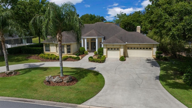 ranch-style house with an attached garage, curved driveway, a chimney, and a front yard