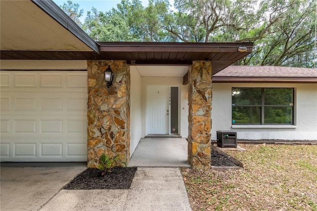 1406 SE Wacahoota Rd, Micanopy, FL 32667 - view of exterior entry featuring stone siding, stucco siding, a garage, and concrete driveway
