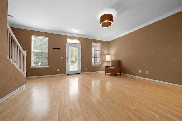 unfurnished room featuring light wood-style floors, stairway, baseboards, and ornamental molding