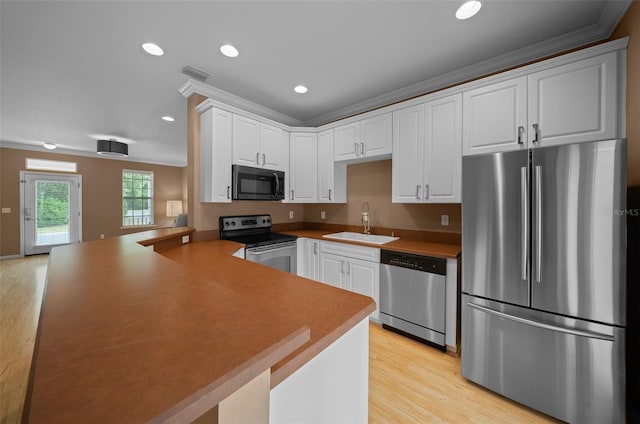 kitchen with light wood finished floors, visible vents, a sink, a peninsula, and stainless steel appliances