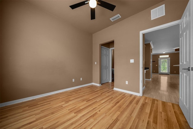 unfurnished bedroom with light wood-style floors, visible vents, baseboards, and lofted ceiling