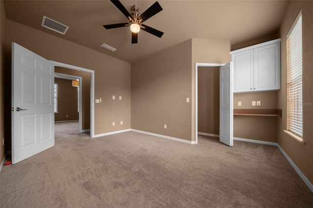 unfurnished bedroom with light colored carpet, multiple windows, and visible vents
