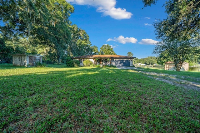 13232 NE 39th Ter, Anthony, FL 32617 - view of yard with a storage unit, fence, an attached garage, and an outbuilding