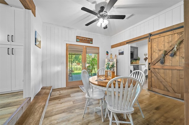 13232 NE 39th Ter, Anthony, FL 32617 - dining space featuring a ceiling fan, separate washer and dryer, wood walls, a barn door, and light wood-style floors