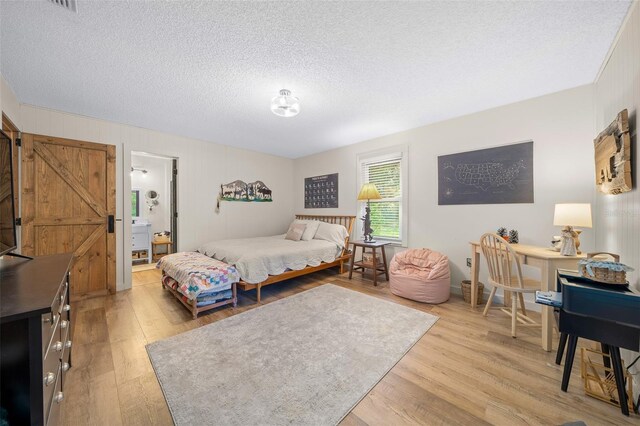 13232 NE 39th Ter, Anthony, FL 32617 - bedroom featuring light wood-style flooring, a textured ceiling, and a barn door