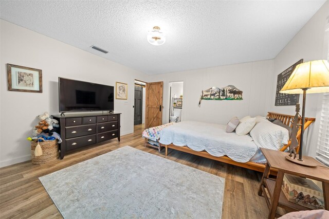 13232 NE 39th Ter, Anthony, FL 32617 - bedroom with a textured ceiling, baseboards, visible vents, and wood finished floors