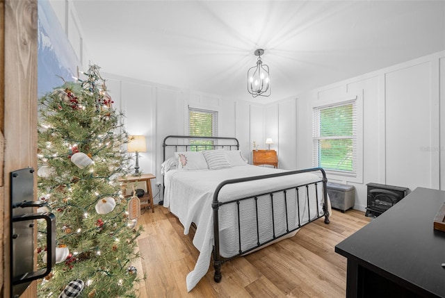 13232 NE 39th Ter, Anthony, FL 32617 - bedroom featuring a decorative wall, a notable chandelier, and light wood-style floors