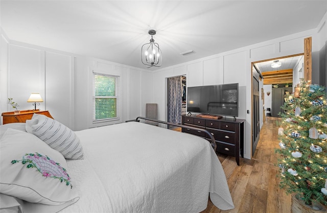 13232 NE 39th Ter, Anthony, FL 32617 - bedroom with a notable chandelier, light wood finished floors, a decorative wall, and visible vents
