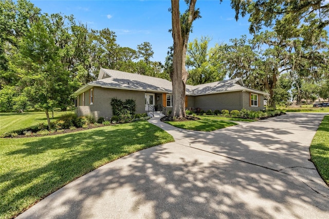 5326 NW 76th Ct, Ocala, FL 34482 - mid-century inspired home with a front lawn, view of scattered trees, and driveway