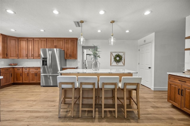 5326 NW 76th Ct, Ocala, FL 34482 - kitchen featuring stainless steel fridge, light wood-type flooring, brown cabinets, decorative backsplash, and recessed lighting