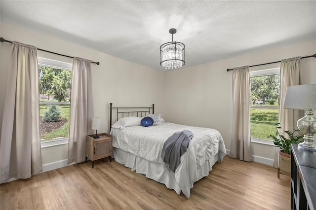 5326 NW 76th Ct, Ocala, FL 34482 - bedroom with light wood-style floors, baseboards, a chandelier, and a textured ceiling
