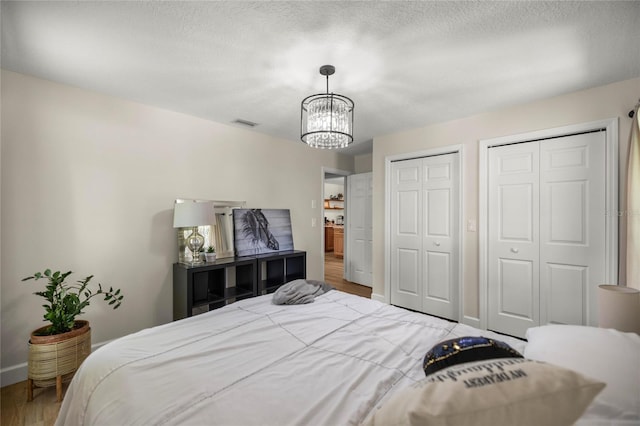 5326 NW 76th Ct, Ocala, FL 34482 - bedroom with two closets, a chandelier, wood finished floors, baseboards, and a textured ceiling