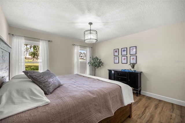 5326 NW 76th Ct, Ocala, FL 34482 - bedroom with baseboards, multiple windows, wood finished floors, a chandelier, and a textured ceiling