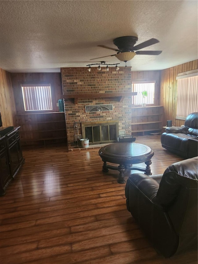 2151 SE 177th Ave, Silver Springs, FL 34488 - living room featuring hardwood / wood-style flooring, a fireplace, a textured ceiling, rail lighting, and wooden walls