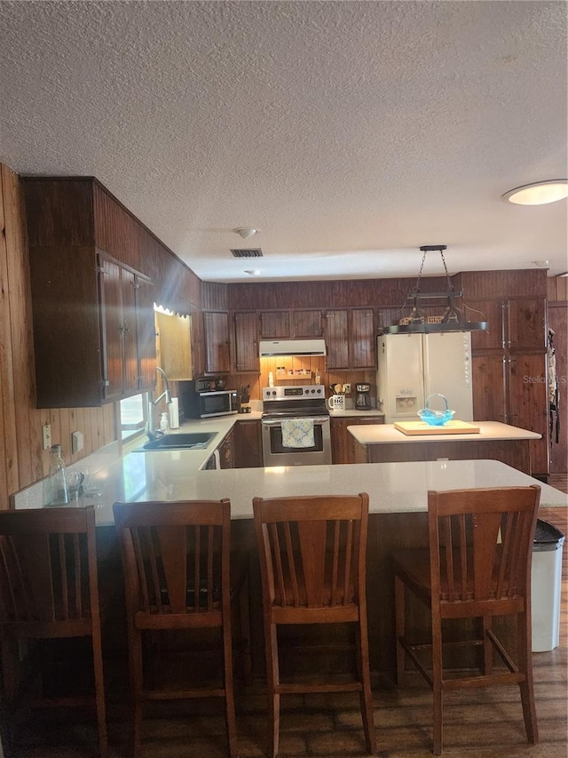 2151 SE 177th Ave, Silver Springs, FL 34488 - kitchen featuring stainless steel appliances, under cabinet range hood, wood walls, a textured ceiling, and light countertops