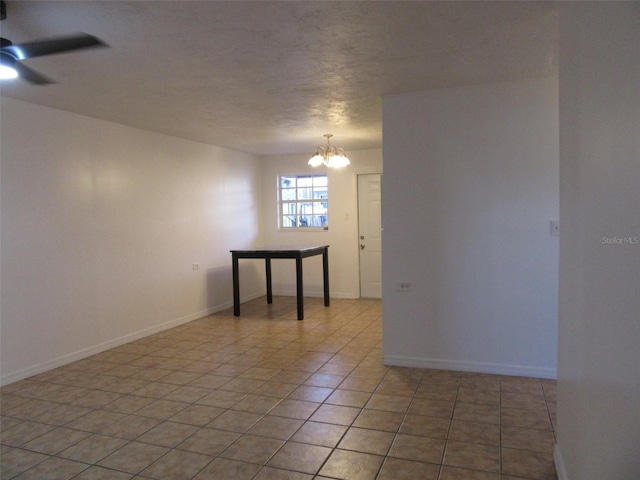 empty room featuring baseboards, ceiling fan with notable chandelier, and light tile patterned flooring