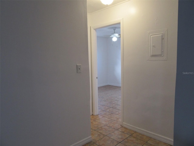 hall featuring light tile patterned floors, baseboards, and electric panel