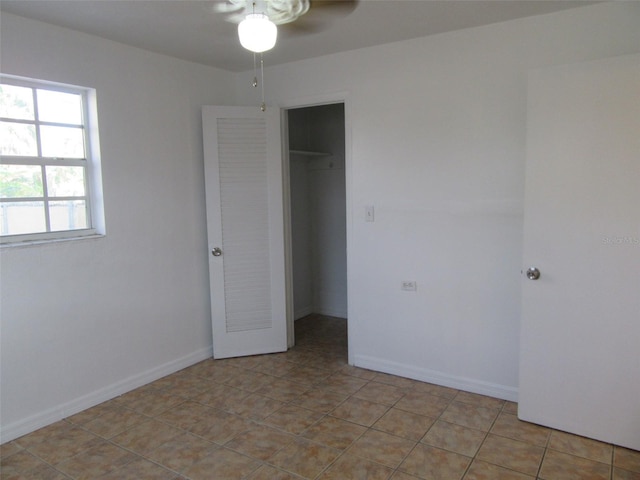unfurnished bedroom with a closet, baseboards, a walk in closet, and light tile patterned floors