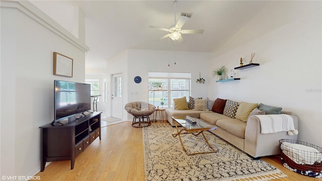 living area with high vaulted ceiling, light wood-type flooring, a ceiling fan, and visible vents