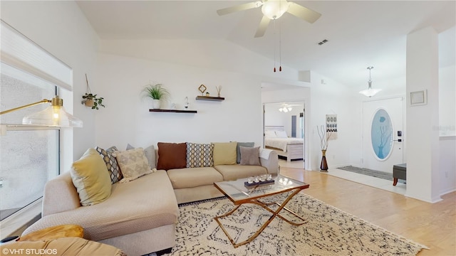 living room featuring ceiling fan, lofted ceiling, visible vents, and wood finished floors