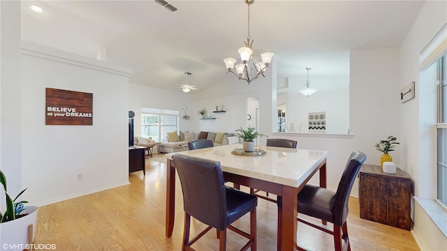 dining space featuring light wood finished floors, visible vents, baseboards, and ceiling fan with notable chandelier